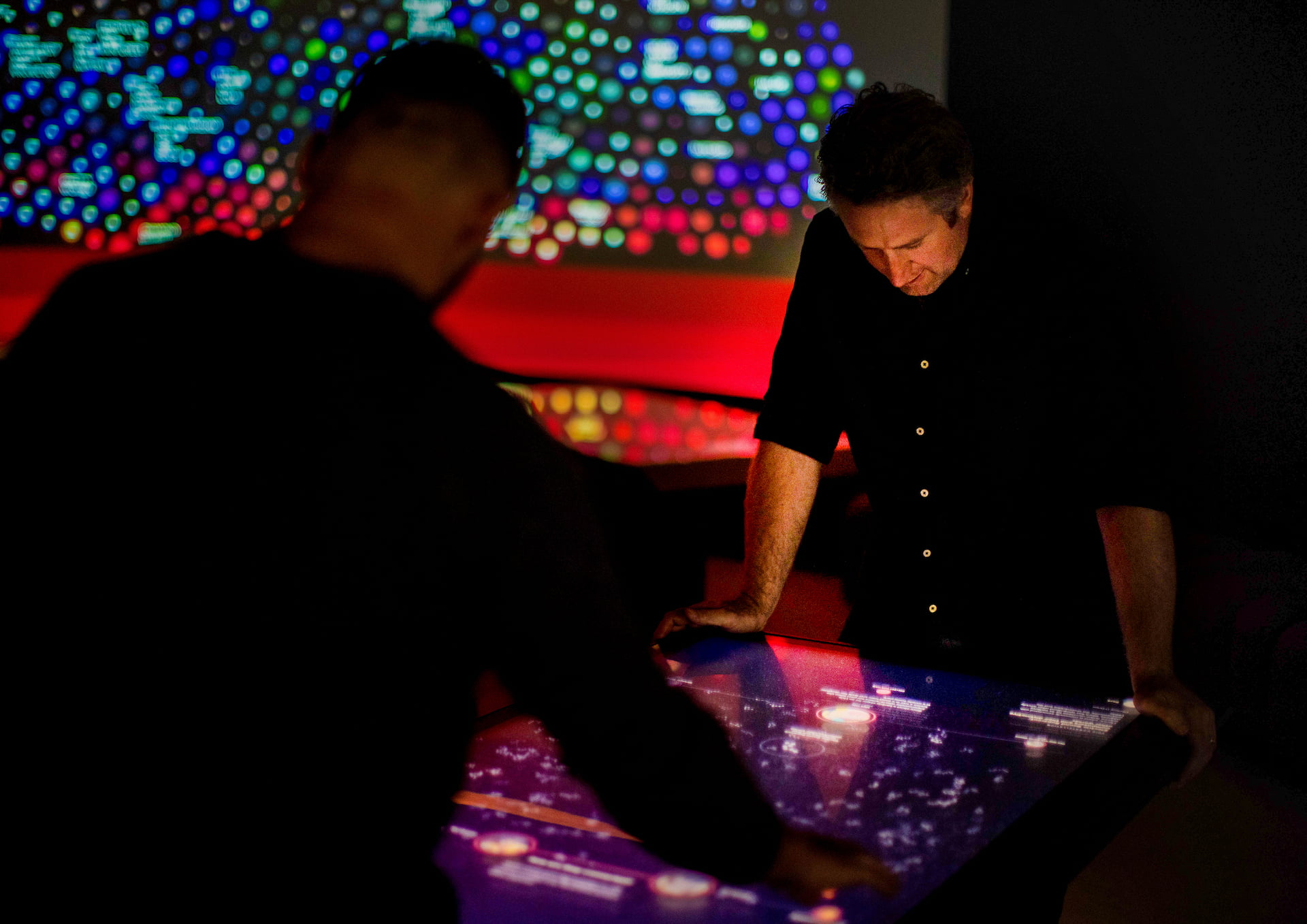 Touch table interaction Man leaning over touchscreen.