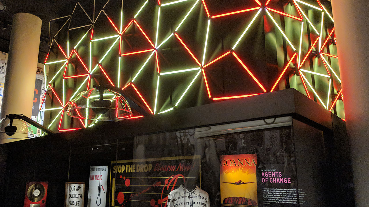 Digital light sculpture Colourful lights of red and white above exhibition glass case.
