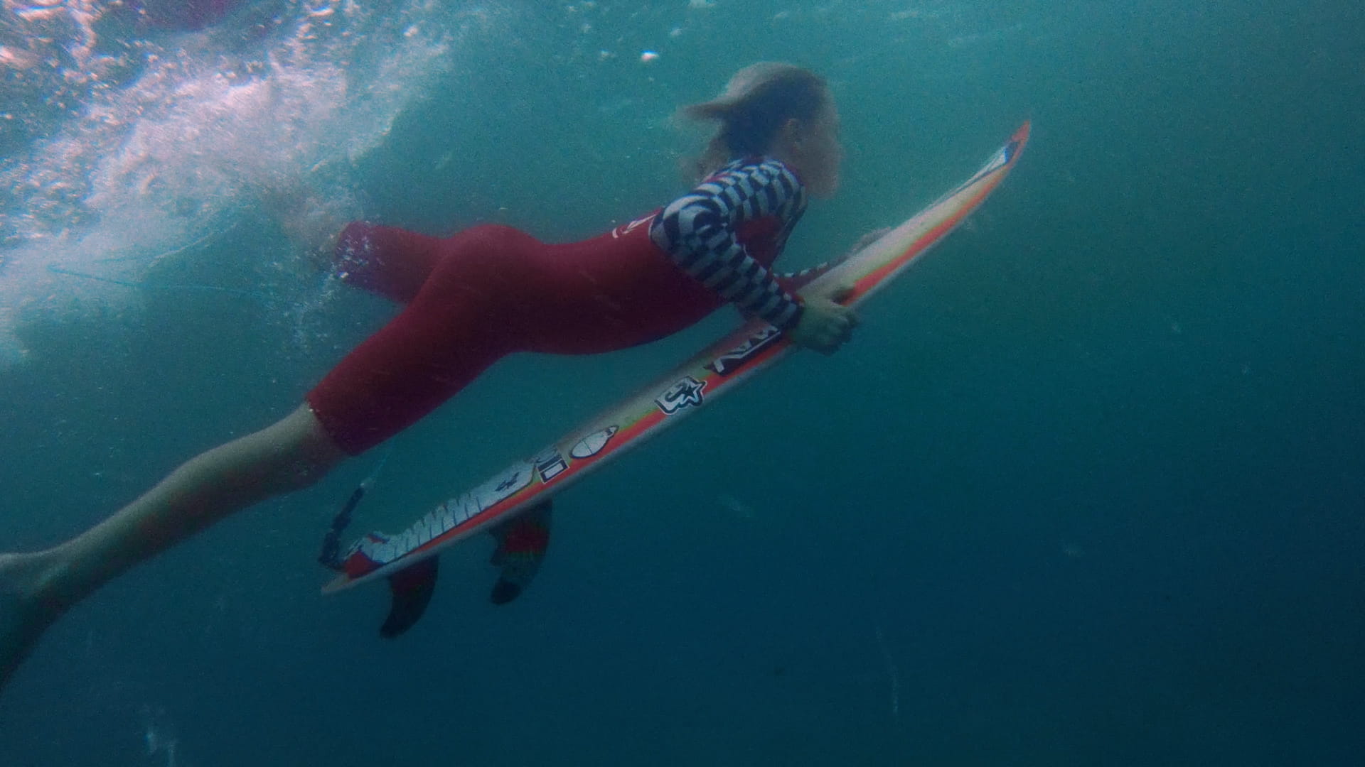 Surf photography Woman diving under a wave on surfboard.