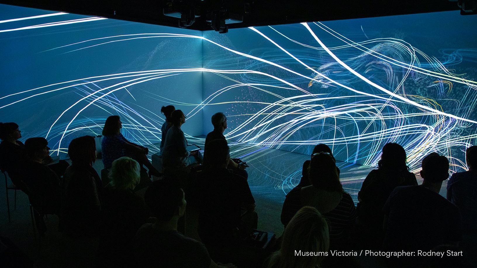 Immersive film Captive audience watch lines of light swirl across two screens.