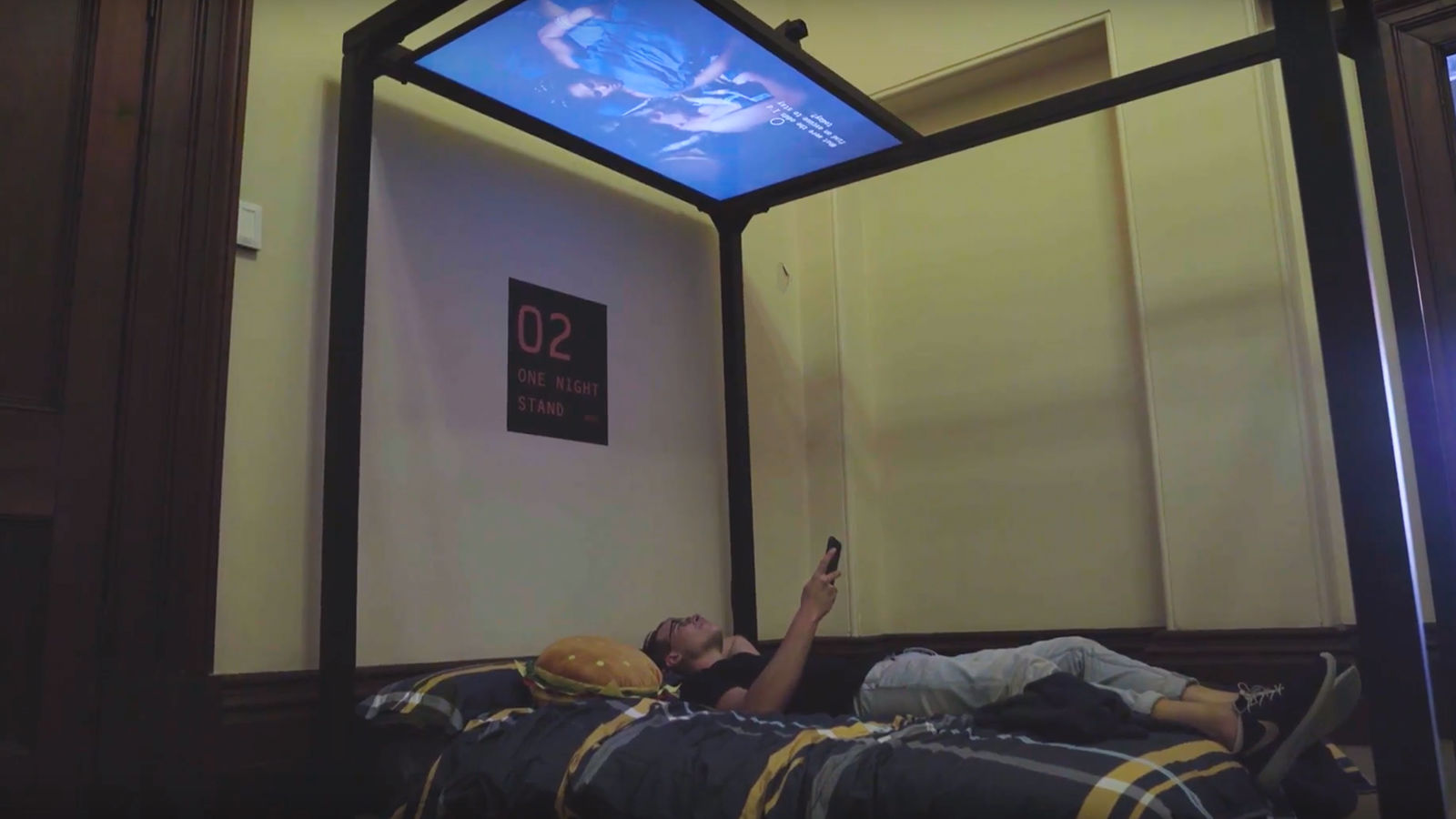 Interactive film installation Man on bed with screen directly above their head.