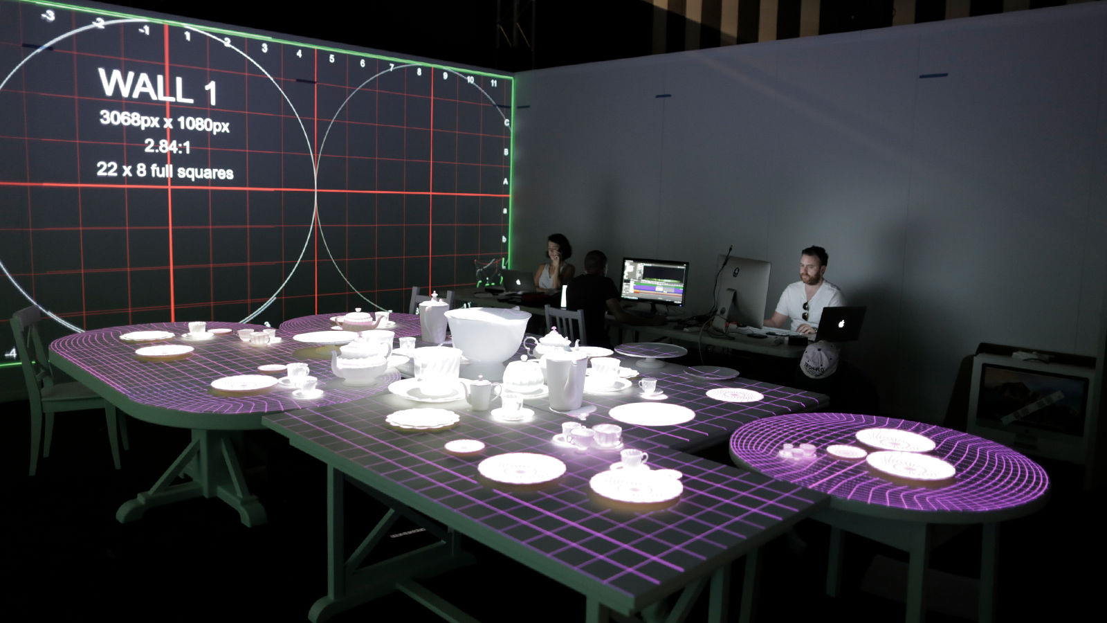 Projection-mapped experience Team of developers calibrating projector alignment on wall and tables.