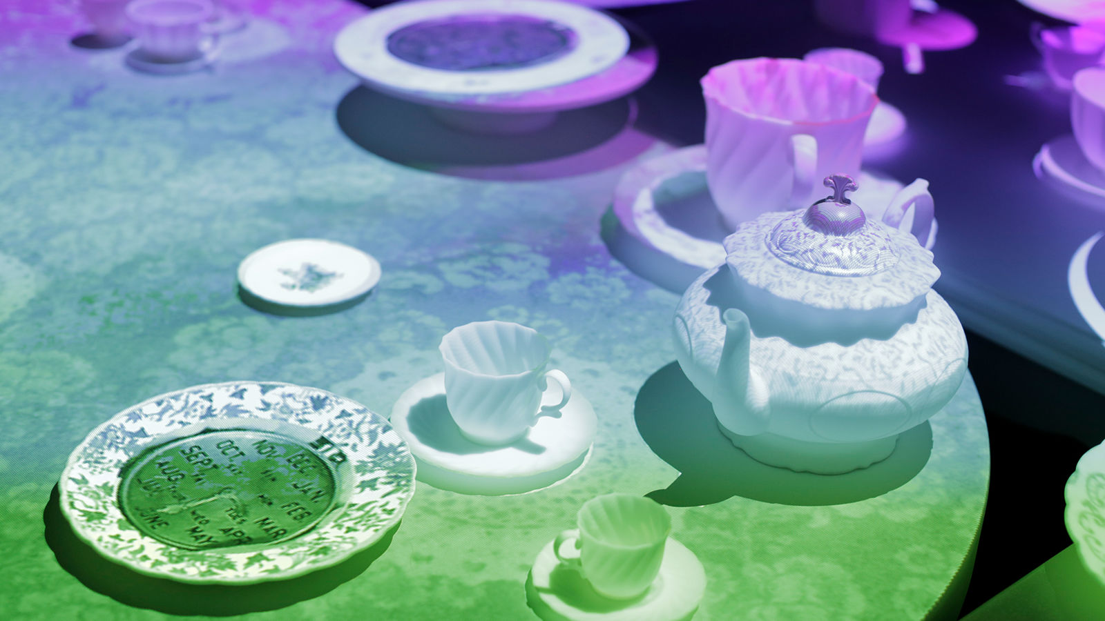 Mad hatter's projection mapping Close-up of teacup, saucer and tea pot with colourful gradient of colour projected on top.