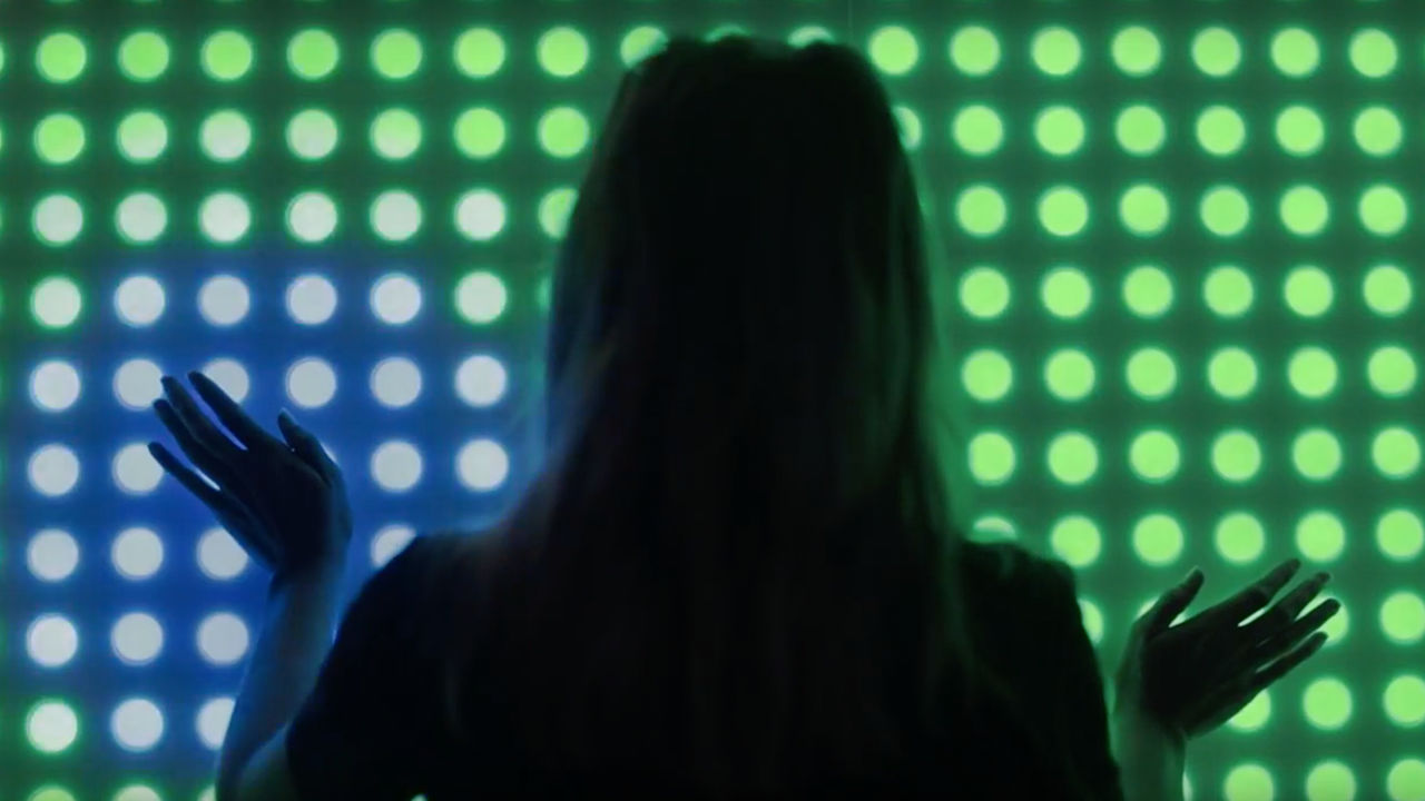 Interactive digital pixel wall Woman touching a screen of blue and green dots.