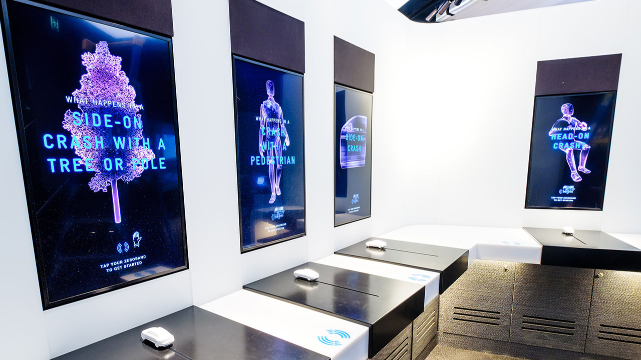 Four vertical portrait screens with interactive white 3D modelled cars below each. 