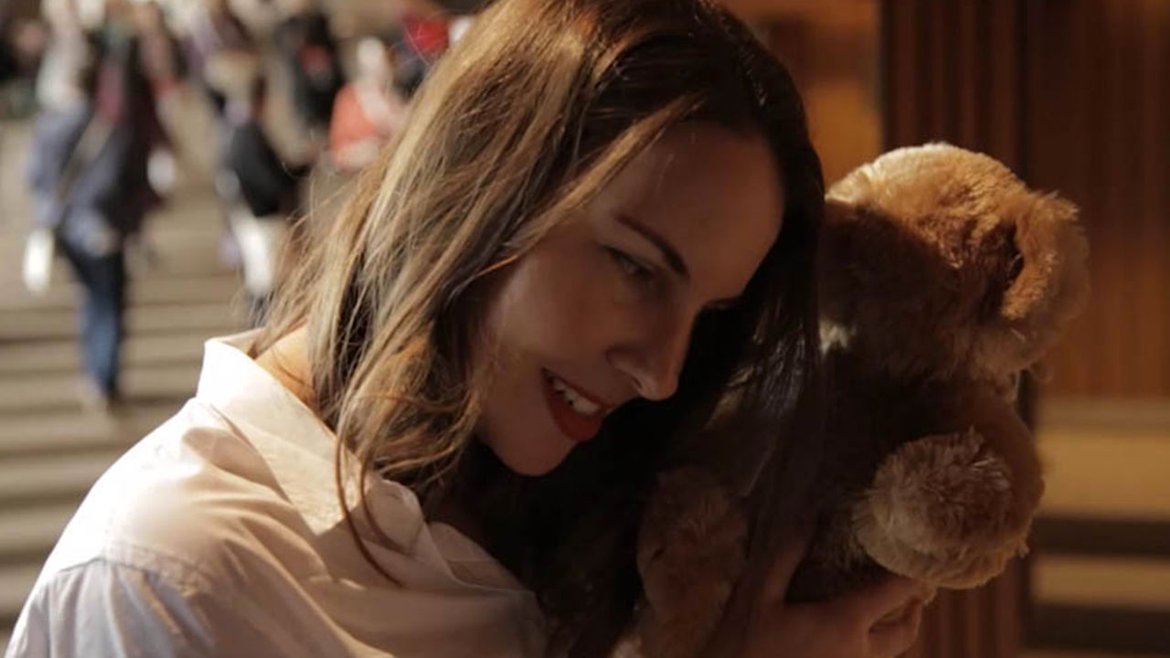 Interactive teddy experience Woman holding a TeddyX bear to her ear in the Opera House.