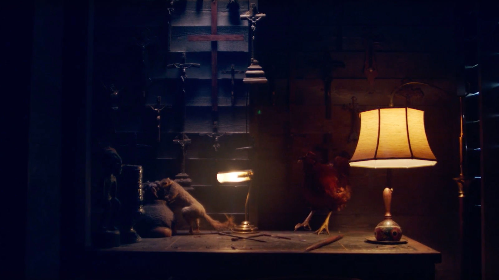 Fallow cross gameplay experience Dusty room with crucifix in background, taxidermied chicken and squirrel on desk.